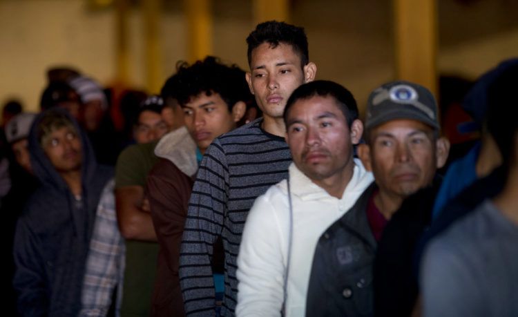 Migrantes hondureños hacen línea para tomar desayuno en un depósito que abrió sus puertas para dar de comer a los migrantes en el centro de Tijuana, México, el martes 18 de diciembre del 2018. Foto: Moisés Castillo / AP.