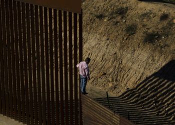 Un migrante se para en la valla fronteriza antes de saltar al lado de Estados Unidos, hacia San Diego, California, desde Tijuana, México, el viernes 28 de diciembre de 2018. Foto: Daniel Ochoa de Olza / AP.
