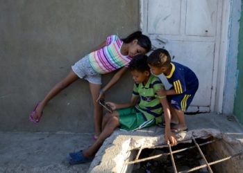 De izquierda a derecha, Solgreidy, de 8 años, Greider, de 10, y Elvis, de 3, mientras hablan con su madre Emili Espinoza a través de una videollamada en la casa de su tío en Punto Fijo, Venezuela. Foto: Fernando Llano / AP.