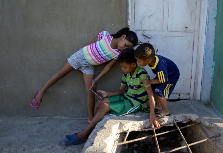 De izquierda a derecha, Solgreidy, de 8 años, Greider, de 10, y Elvis, de 3, mientras hablan con su madre Emili Espinoza a través de una videollamada en la casa de su tío en Punto Fijo, Venezuela. Foto: Fernando Llano / AP.