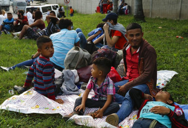Freddy Rivas (segundo por la derecha), natural de Tocoa, Honduras, sus hijos Josué (izquierda) y Elkin (centro) y su hermano Mario esperan la llegada de más migrantes a una caravana que viajará hacia la frontera de Estados Unidos, en San Pedro Sula, Honduras, el 14 de enero de 2019. (AP Foto/Delmer Martinez)