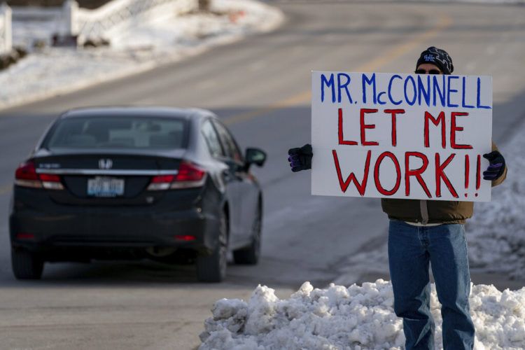 Un trabajador de la Agencia de Protección Ambiental de EEUU (EPA, por sus siglas en inglés) afectado por el cierre parcial del gobierno protesta con un cartel ante las oficinas del senador Mitch McConnell, en Park Hills, Kentucky, el 22 de enero de 2019. Foto: Bryan Woolston / AP.