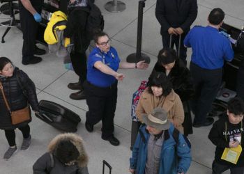 Una agente de la Administración de Seguridad en el Transporte, centro, da instrucciones a los pasajeros en un punto de revisión en el Aeropuerto Internacional John F. Kennedy, en Nueva York. Foto: Mark Lennihan / AP.