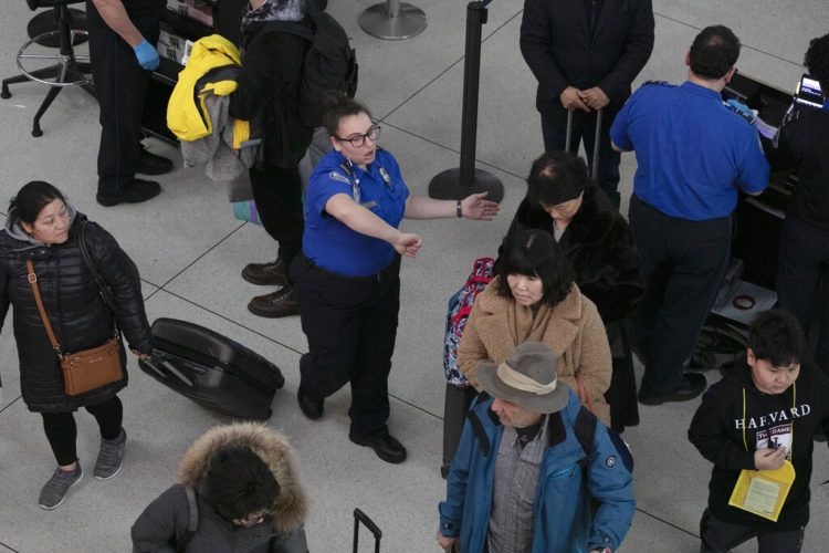 Una agente de la Administración de Seguridad en el Transporte, centro, da instrucciones a los pasajeros en un punto de revisión en el Aeropuerto Internacional John F. Kennedy, en Nueva York. Foto: Mark Lennihan / AP.