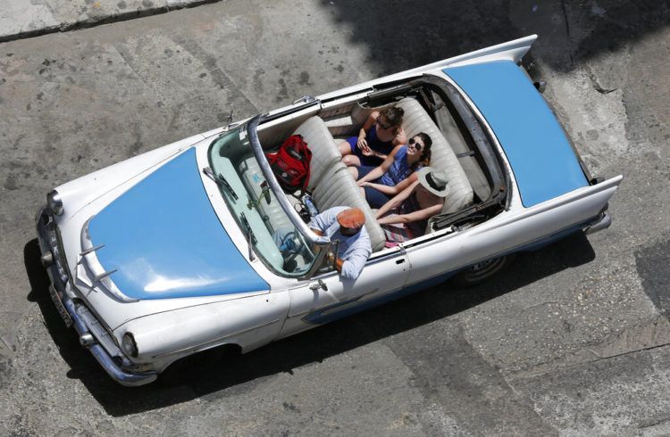En esta imagen tomada el 13 de mayo de 2015, turistas pasean en un auto clásico descapotable por La Habana. Foto: Desmond Boylan / AP.