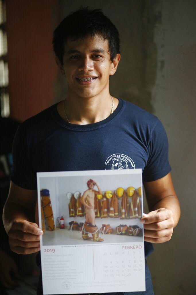 El bombero Daniel Rodríguez muestra la página del calendario en la que posa desnudo, en Asunción, Paraguay. Foto: Jorge Saenz / AP.