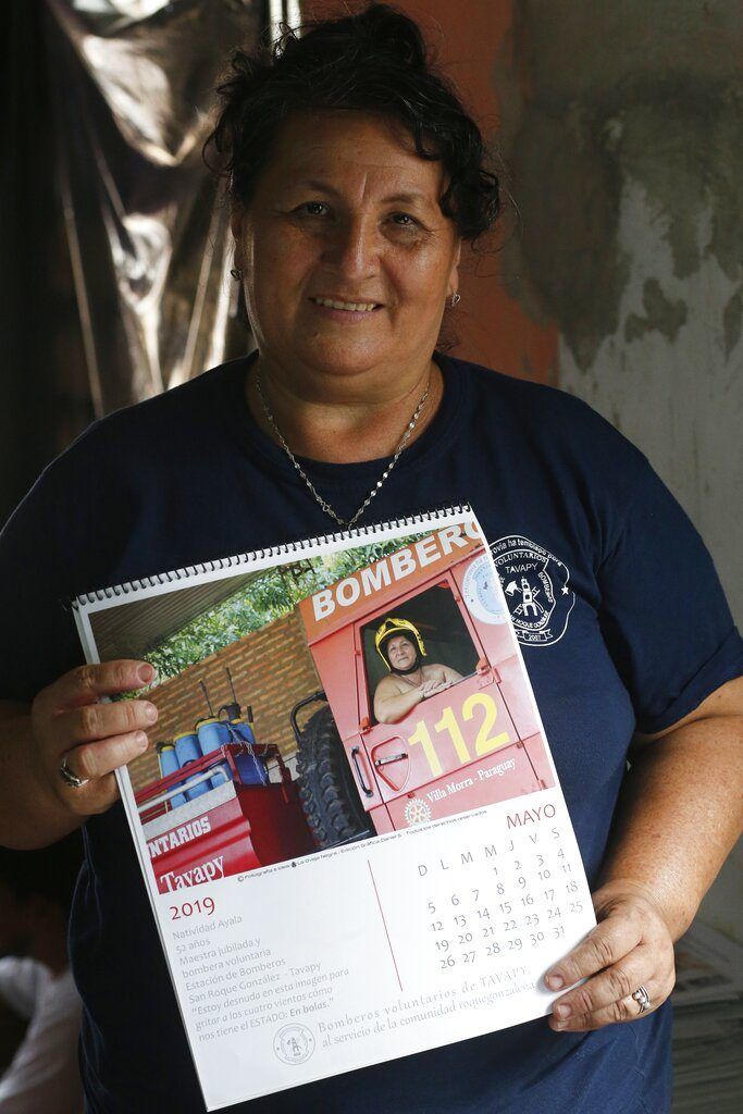 La bombero Natividad Ayala García muestra la página del calendario en la que posa desnuda dentro de un camión del departamento, en Asunción, Paraguay. Foto: Jorge Saenz / AP.