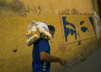 El venezolano Carlos González lleva una bolsa con alimentos entregada por el gobierno a los más pobres, en el barrio Antimano de Caracas, 29 de enero de 2019. Foto: Rodrigo Abd / AP.