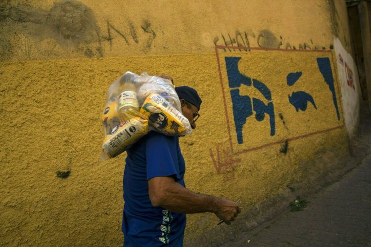 El venezolano Carlos González lleva una bolsa con alimentos entregada por el gobierno a los más pobres, en el barrio Antimano de Caracas, 29 de enero de 2019. Foto: Rodrigo Abd / AP.