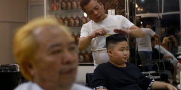 A Le Phuc Hai de 66 años, izquierda, y To Gia Huy, de 9 años, les cortan el cabello al estilo Trump y Kim en Hanoi, Vietnam, el martes 19 de febrero de 2019. Foto: Hau Dinh / AP.