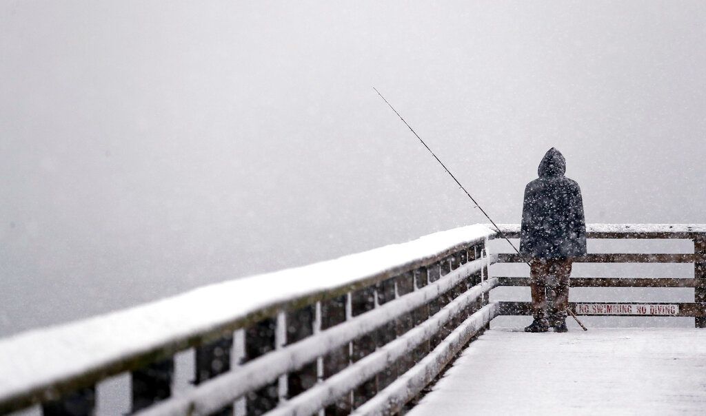 Hershel Odle mira al horizonte, completamente blanco por una tormenta de nieve, mientras pesca en un muelle el viernes 8 de febrero del 2019, en Seattle. Foto: Elaine Thompson / AP.