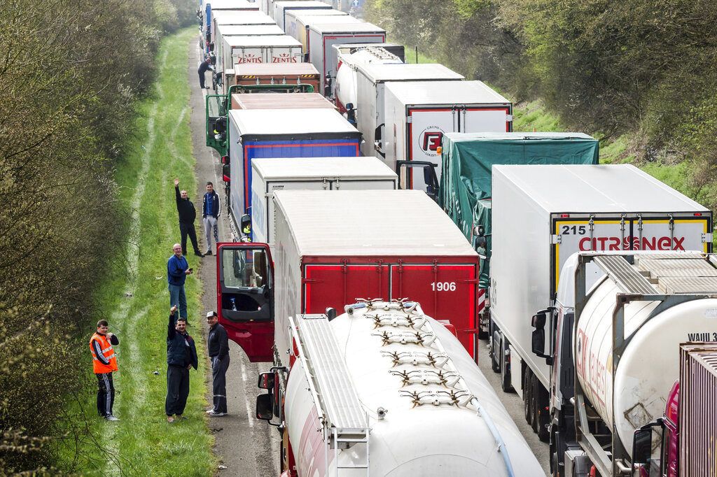Conductores de camión esperan junto a sus vehículos en una autopista entre Bruselas y Luxemburgo, en Spontin, Bélgica, 6 de abril de 2016. Foto: Geert Vanden Wijngaert / AP.