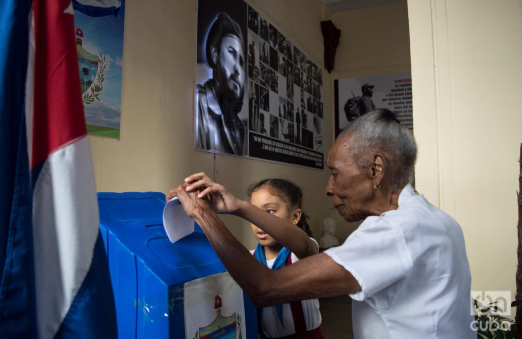 Una señora débil visual vota en un colegio electoral de la Habana Vieja, auxiliada por una niña, en el referendo constitucional cubano el 24 de febrero de 2019. Foto: Otmaro Rodríguez.