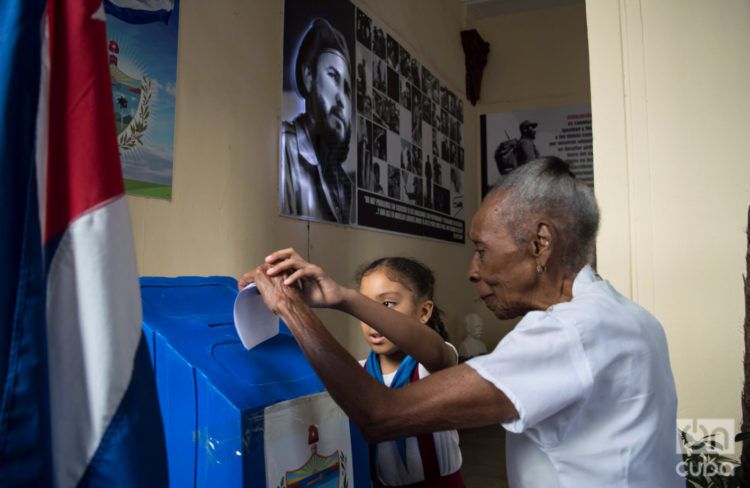 Una señora débil visual vota en un colegio electoral de la Habana Vieja, auxiliada por una niña, en el referendo constitucional cubano el 24 de febrero de 2019. Foto: Otmaro Rodríguez.