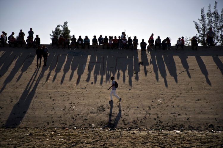 Migrantes cerca del paso fronterizo del Chaparral observan los enfrentamientos con la patrulla fronteriza de Estados Unidos, vistos desde Tijuana, México. (AP Foto/Ramón Espinosa, archivo)