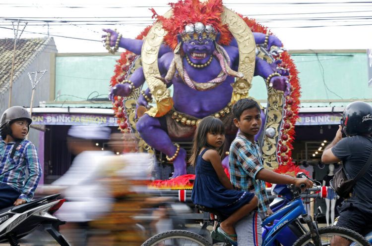 Dos niños en bicicleta pasan por delante de una escultura gigante conocida como "ogoh-ogoh", que representa a los espíritus malvados para celebrar el Nyepi, el día anual del silencio que celebra el inicio del año nuevo hindú balinés, en Bali, Indonesia, el 6 de marzo de 2019. Foto: Firdia Lisnawati / AP.