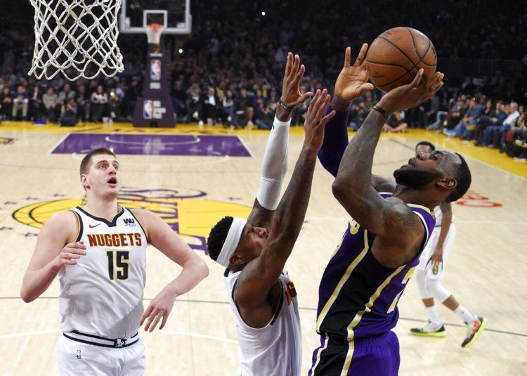 LeBron James, de los Lakers de Los Ángeles (derecha), lanza a canasta ante sus rivales de los Nuggets de Denver Torrey Craig (centro) y Nikola Jokic, durante la primera mitad del juego de la NBA que enfrentó a ambos equipos, el 6 de marzo de 2019, en Los Ángeles. (AP Foto/Mark J. Terrill)