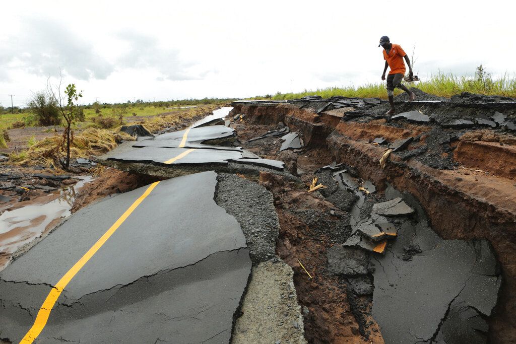 Un hombre cruza por una parte de una carretera dañada por el paso del ciclón Idai en Nhamatanda, Mozambique, aproximadamente a 50 kilómetros (30 millas) de Beira, el viernes 22 de marzo de 2019. (AP Foto/Tsvangirayi Mukwazhi)
