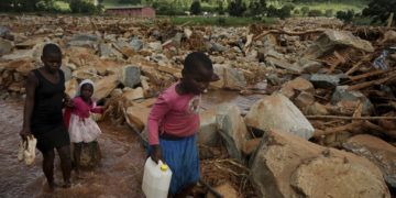 En imagen del viernes 22 de marzo de 2019, un grupo de menores cruza un riachuelo en Chimanimani, Zimbabue, en una zona devastada tras el paso de un ciclón en el sur de África. (AP Foto/KB Mpofu)