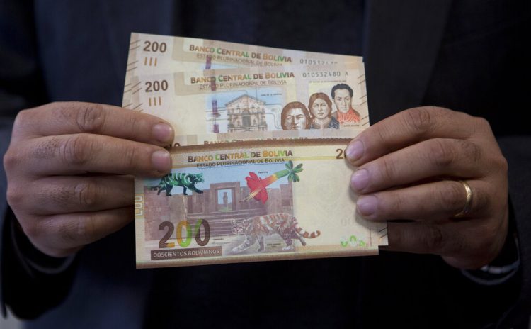 Un empleado del Banco Central de Bolivia maneja los nuevos billetes de 200 bolivianos durante una ceremonia en el palacio de gobierno de La Paz, el martes 23 de abril de 2019. (AP Foto / Juan Karita)