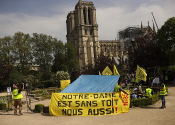 Defensores de la vivienda pública protestan frente a la destruida catedral de Notre Dame para exigir que se recuerde a los más pobres de Francia, en París, el lunes 22 de abril de 2019. Foto: Francisco Seco / AP.