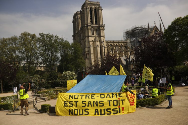 Defensores de la vivienda pública protestan frente a la destruida catedral de Notre Dame para exigir que se recuerde a los más pobres de Francia, en París, el lunes 22 de abril de 2019. Foto: Francisco Seco / AP.