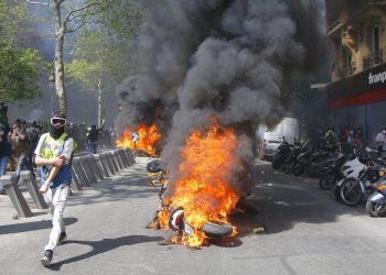 Un hombre corre junto a una motocicleta en llamas durante una protesta de chalecos amarillos en París, el sábado 20 de abril de 2019. Foto: Michel Euler/AP.