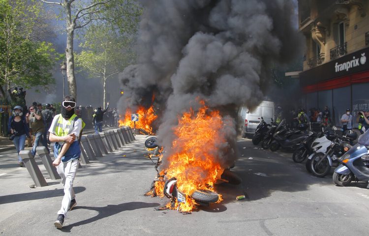 Un hombre corre junto a una motocicleta en llamas durante una protesta de chalecos amarillos en París, el sábado 20 de abril de 2019. Foto: Michel Euler/AP.
