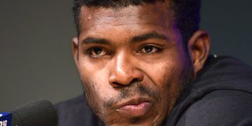 El cubano Yasiel Puig, de los Rojos de Cincinnati, hace una mueca mientras escucha preguntas de los reporteros antes del partido frente a los Dodgers de Los Ángeles, el lunes 15 de abril de 2019, en Los Ángeles. (AP Foto/Mark J. Terrill)