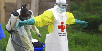 Fotografía de archivo del 9 de septiembre de 2018 de un trabajador rociando desinfectante a su colega luego de trabajar en un centro de tratamiento de ébola en Beni, Congo. Foto: AP/Al-hadji Kudra Maliro\Archivo.