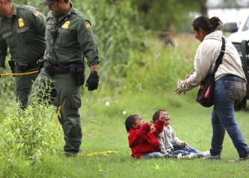 Una hondureña y sus dos hijos permanecen cerca de agentes de la Patrulla Fronteriza 10 de mayo de 2019 en el río Grande, cerca de Eagle Pass, en Texas, donde numerosas personas estaban cruzando a suelo estadounidense desde México en balsas. Foto: Bob Owen / The San Antonio Express-News vía AP.