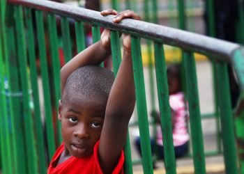 Un niño haitiano agarra una barrera en un centro de detención migratorio donde migrantes han acampado por semanas esperando respuesta a sus solicitudes de asilo en Tapachula, México, el miércoles 29 de mayo de 2019. Foto: Marco Ugarte / AP.