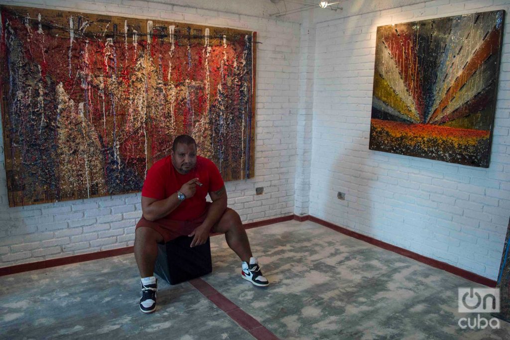 El artista cubano Michel Mirabal junto a obras de la exposición personal que exhibe en su galería taller, como parte de las actividades colaterales de la XIII Bienal de La Habana. Foto: Otmaro Rodríguez.