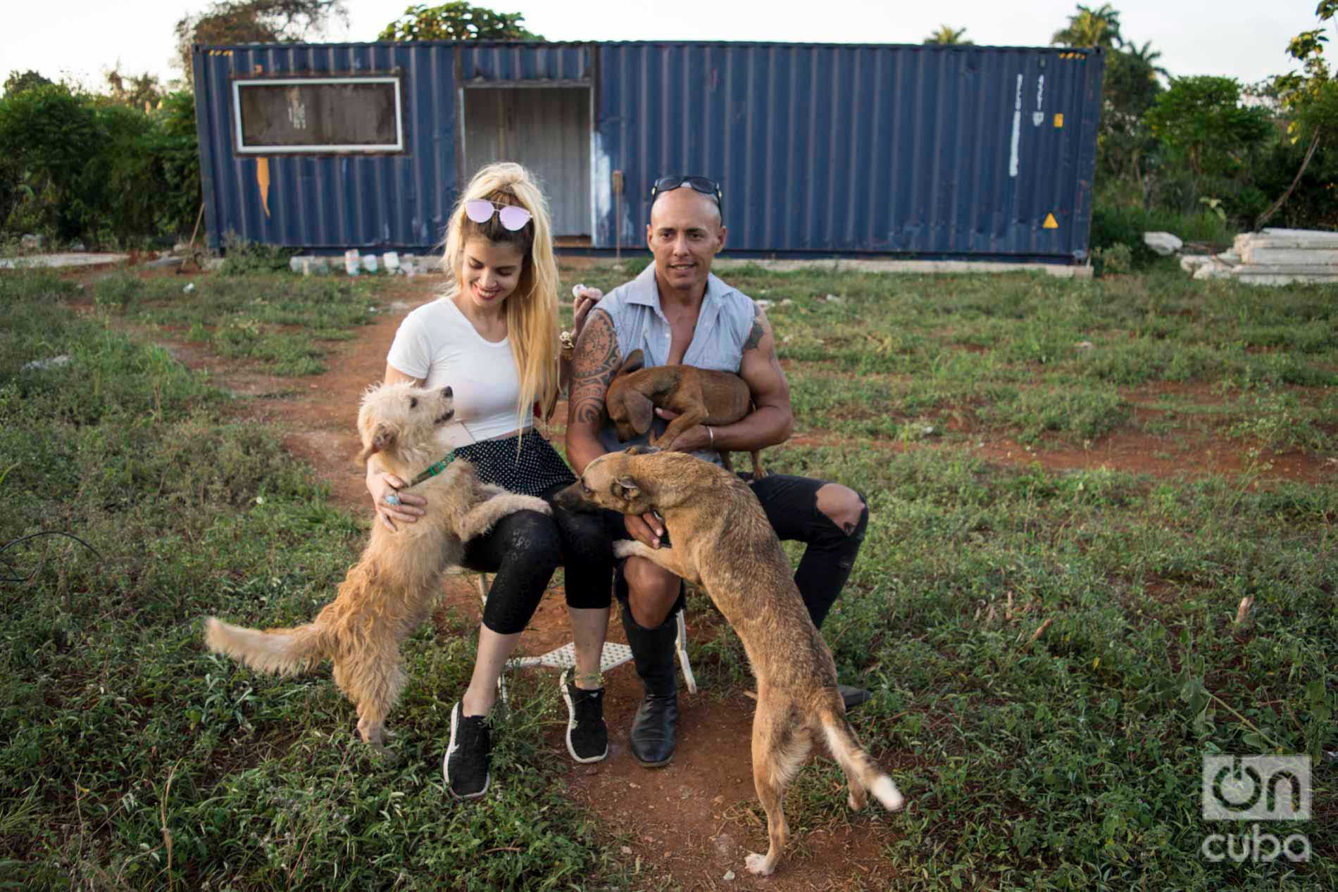 Venus y Ernesto con varios de los perros de su refugio. Detrás, el contenedor que adaptarán como casa mientras construyen su nueva vivienda. Foto: Otmaro Rodríguez.