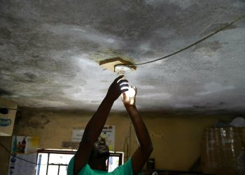 En esta imagen, tomada el 16 de abril de 2019, Johny Legagneur cambia una bombilla para un cliente en su tienda en Petion-Ville, Haití. Johny vive de cargar computadoras personales, celulares y bombillas recargables con un generador. (AP Foto/Dieu Nalio Chery)