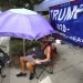 Ray Renaud, de Daytona Beach, Florida, se cubre con una sombrilla mientras simpatizantes del presidente Donald Trump acampan frente al Amway Center el lunes 17 de junio de 2019, antes de un evento para dar inicio a la campaña de reelección 2020 en Orlando, Florida. (Joe Burbank/Orlando Sentinel via AP)