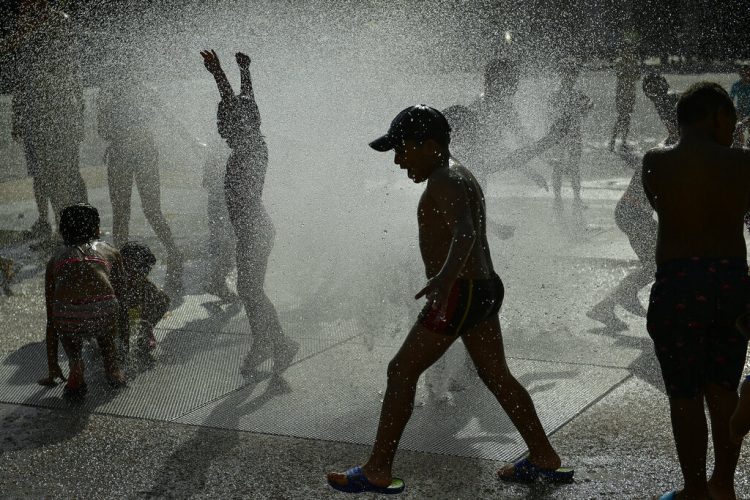 Un grupo de personas se refresca del calor veraniego en una fuente en Pamplona, en el norte de España, el 25 de junio de 2019. Foto: Álvaro Barrientos / AP.