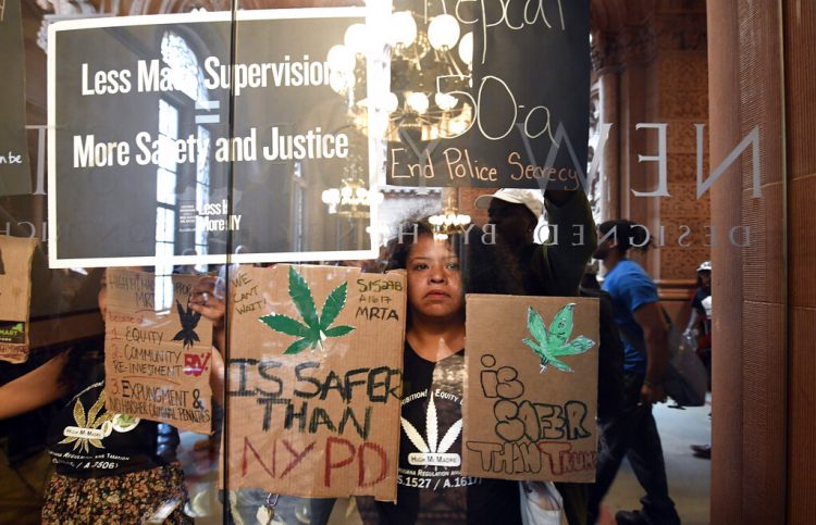Pilar DeJesus, junto con una coalición de manifestantes, sostiene un letrero exhortando a los legisladores a aprobar la posesión de marihuana contra las puertas del Senado en el Capitolio estatal el miércoles 19 de junio de 2019 en Albany, Nueva York. Foto: Hans Pennink / AP.