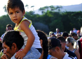 Un venezolano con un niño sobre los hombros espera para cruzar el puente internacional Simón Bolívar a Cúcuta, Colombia, sábado 8 de junio de 2019. Foto: Ferley Ospina / AP.