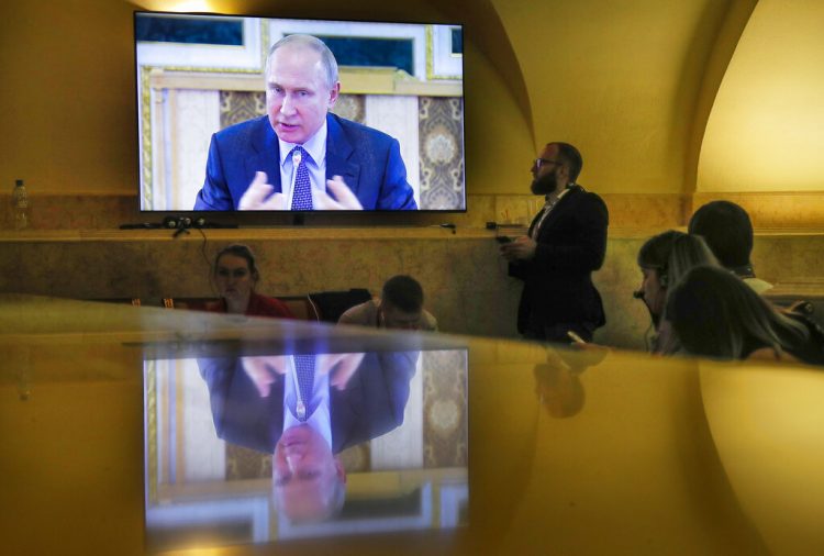 Periodistas observan una pantalla donde se ve al presidente ruso Vladimir Putin en una reunión con jefes de agencias de noticias internacionales en el Foro Económico Internacional en San Petersburgo, Rusia, el jueves 6 de junio de 2019. (AP Foto/Dmitri Lovetsky)