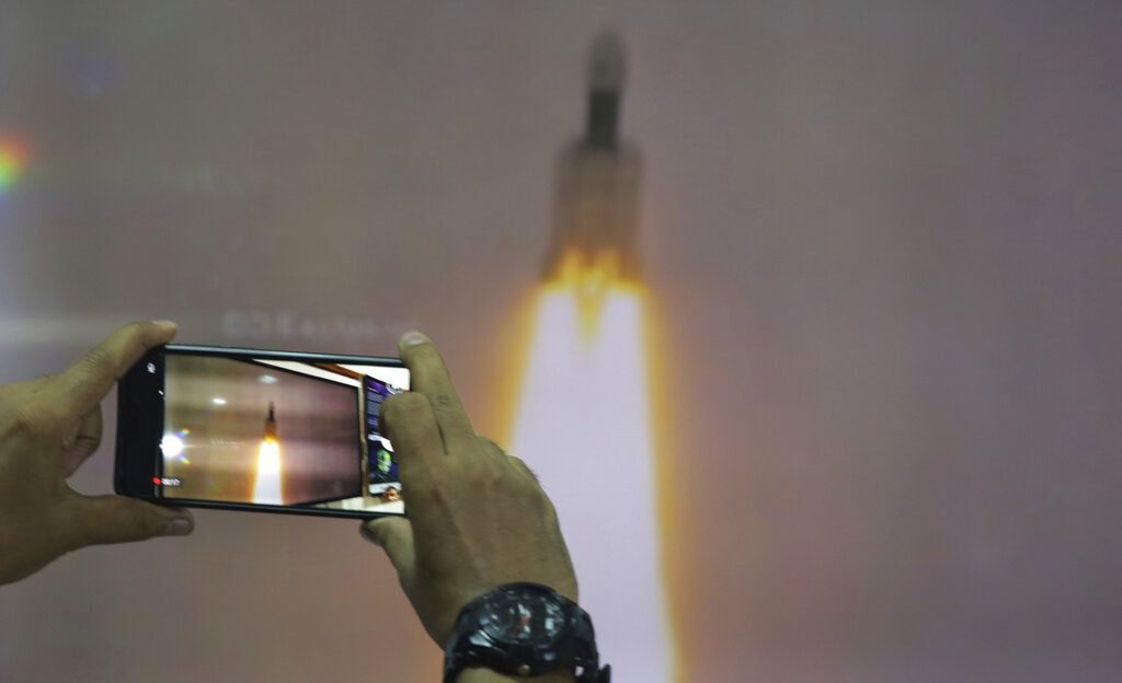 Un hombre en el Planetario Nehru de Nueva Delhi toma fotos de la transmisión por internet del despegue del vehículo de lanzamiento satelital Geosynchronous de la Organización de Investigación Espacial India en el centro espacial Satish Dhawan en la India. Foto: Manish Swarup / AP.