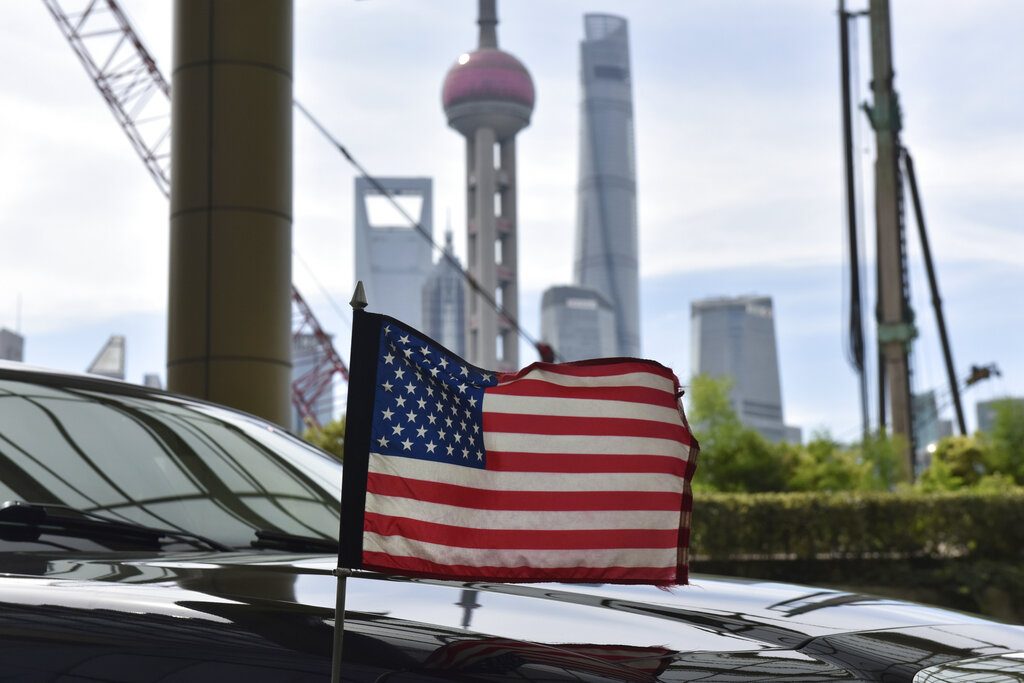 Una bandera de Estados Unidos ondea en un auto del consulado, delante de los edificios del distrito financiero de Lujiazui, en el exterior del hotel donde se alojan los negociadores comerciales de EEUU durante los contactos con sus homólogos chinos, en Shanghái, el 31 de julio de 2019. Foto: Greg Baker/Pool vía AP.