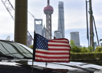Una bandera de Estados Unidos ondea en un auto del consulado, delante de los edificios del distrito financiero de Lujiazui, en el exterior del hotel donde se alojan los negociadores comerciales de EEUU durante los contactos con sus homólogos chinos, en Shanghái, el 31 de julio de 2019. Foto: Greg Baker/Pool vía AP.