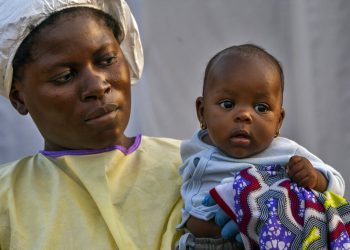 En esta image, tomada el 17 de julio de 2019, Lahya Kathembo, de dos meses, espera en los brazos de una enfermera a los resultados de una prueba de ébola en un centro de tratamiento de la enfermedad en Beni, República Democrática del Congo. (AP Foto/Jerome Delay)