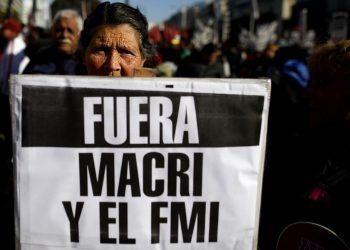 Una mujer sostiene un letrero que pide la salida del presidente Mauricio Macri y el Fondo Monetario Internacional mientras se realizan protestas contra políticas económicas y medidas de austeridad impuestas por el gobierno en Buenos Aires, Argentina, el jueves 22 de agosto de 2019. (AP Foto/Natacha Pisarenko)