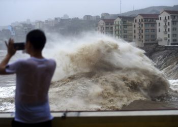 Un hombre graba con su celular el fuerte oleaje causado por la cercanía del tifón Lekima, en la ciudad de Wenling, en el la provincia oriental china de Zhejiang. (Han Chuanhao/Xinhua vía AP)