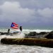 Una mujer posa para una fotografía con el mar y una bandera de Puerto Rico de fondo tras el paso de la tormenta tropical Dorian por la isla, en San Juan, Puerto Rico, el 28 de agosto de 2019. Foto: Ramón Espinosa/ AP.