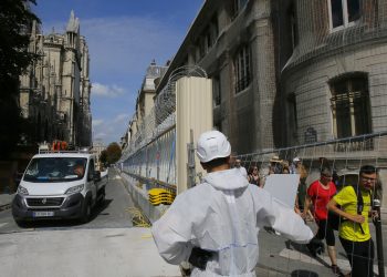 Un trabajador vestido con un overol blanco abre la puerta de la cerca que rodea a la catedral de Notre Dame, en París, el jueves 1 de agosto de 2019, mientras comienzan las labores preliminares para reparar los daños del incendio. Foto: Michel Euler / AP.