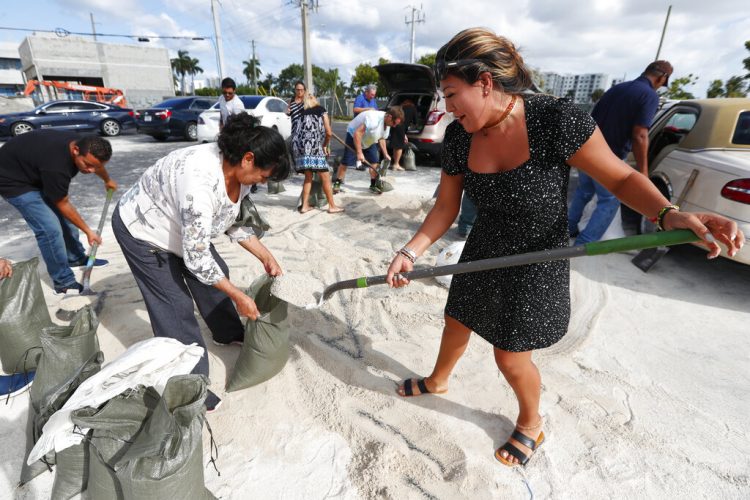 Georgia Bernard (derecha) y Ana Pérez, junto a otros residentes, llenan sacos de arena para llevárselos a casa antes de la llegada del potente huracán Dorian, el 30 de agosto de 2019, en Hallandale Beach, Florida. Foto: Wilfredo Lee/ AP.