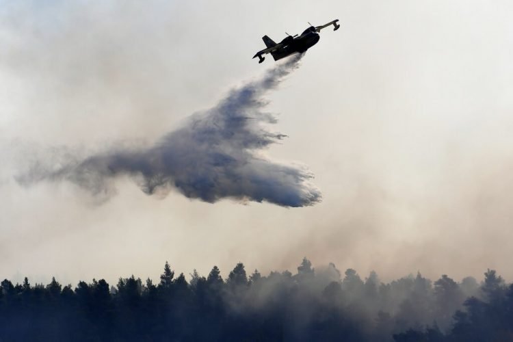 Un avión descarga agua sobre un incendio cerca de la localidad de Halkida, en la isla griega de Evia, el miércoles 14 de agosto de 2019. Foto: Michael Varaklas / AP.